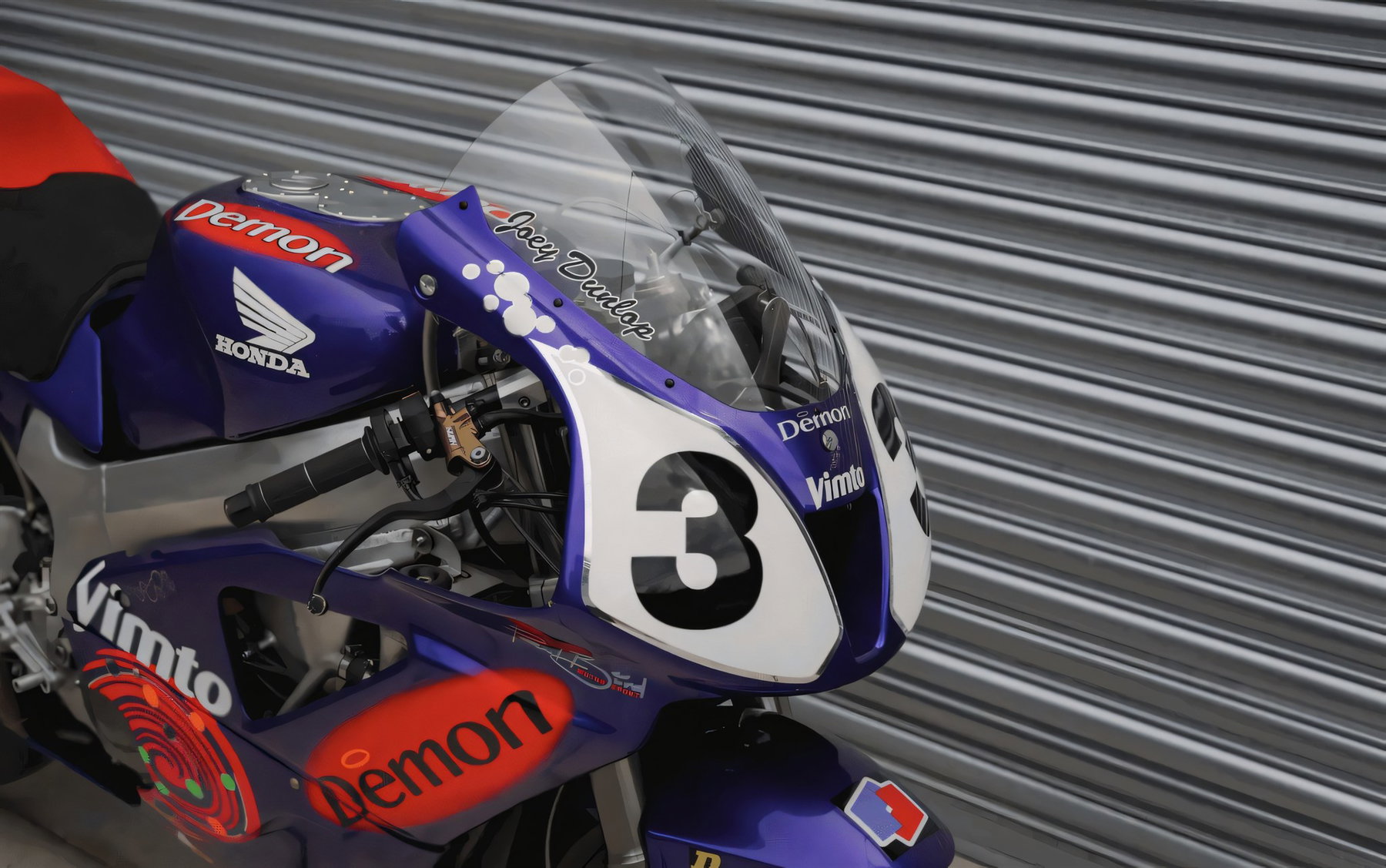 Nahaufnahme von Cockpit und Frontverkleidung der Honda VTR1000 SP-1 mit Startnummer 3, Vimto- und Demon-Logos sowie dem handschriftlichen Schriftzug Joey Dunlop auf der Scheibe