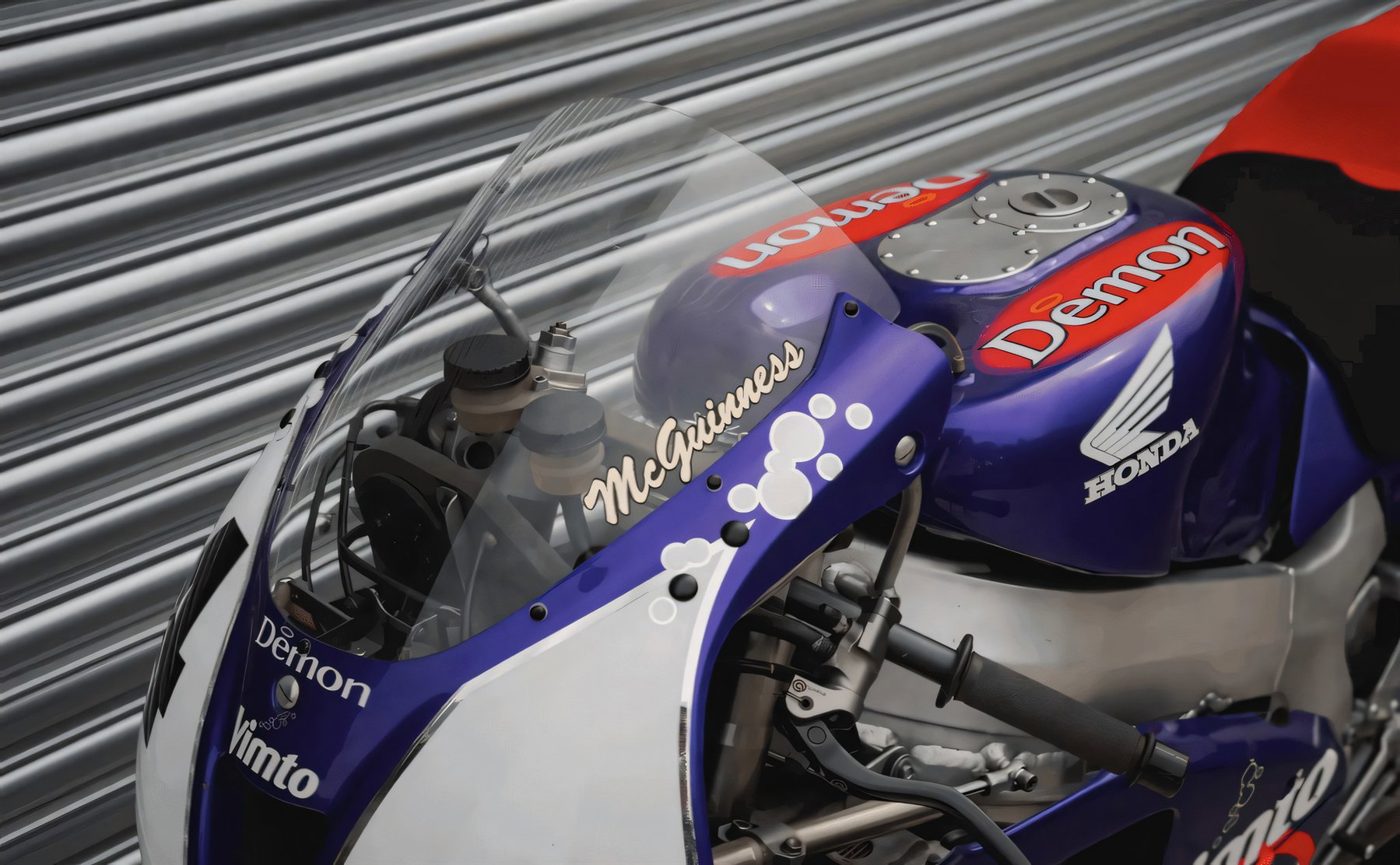 Nahaufnahme des Tankbereichs der Honda VTR1000 SP-1 mit Demon- und Vimto-Logos, Honda-Schriftzug und dem Namenszug McGuinness auf der Verkleidung
