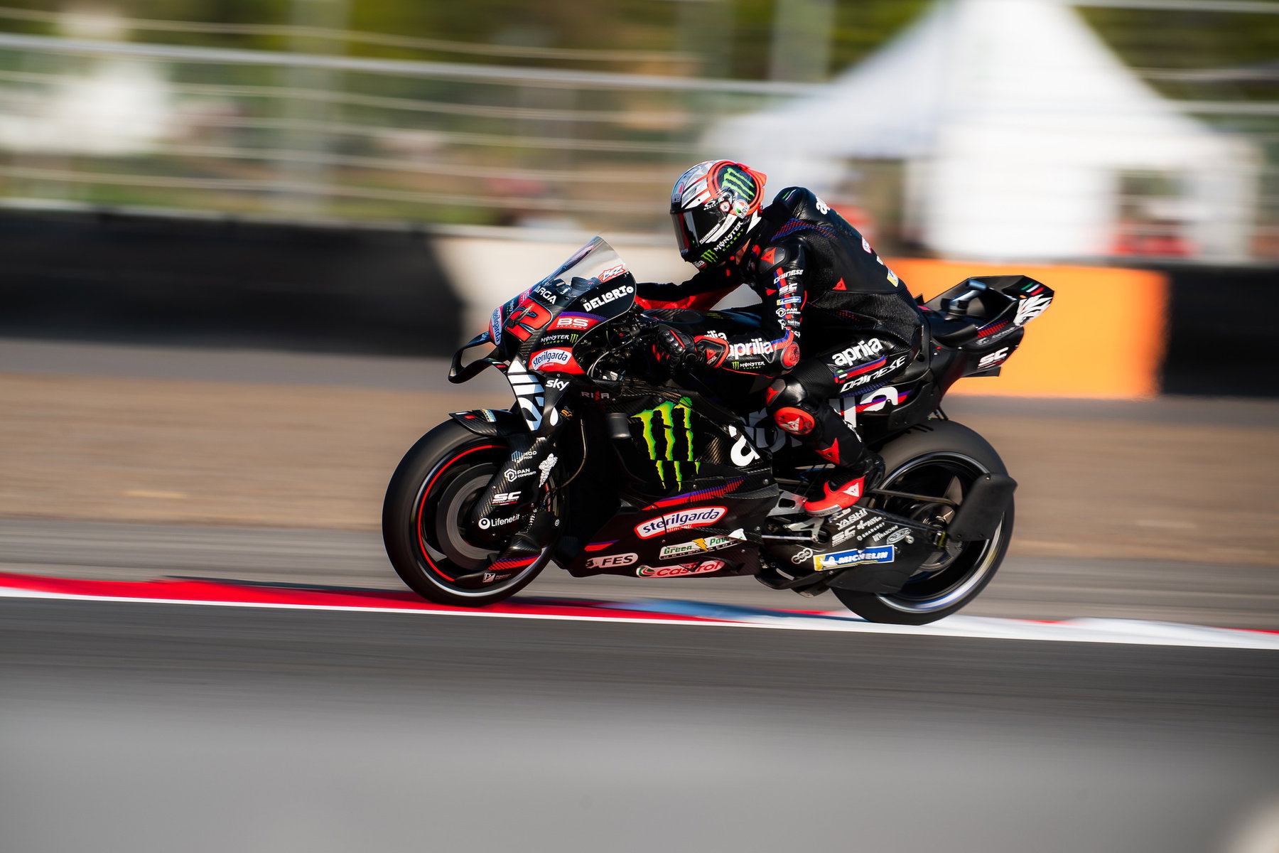 Aprilia-Vierfachsieg in Mandalika: Bezzecchi gewinnt, Martin führt wieder 1 Marco Bezzecchi in Schräglage auf der schwarzen Aprilia RS-GP mit Monster-Energy-Logo, mitgezogener Hintergrund – MotoGP Indonesien-GP Mandalika 2026