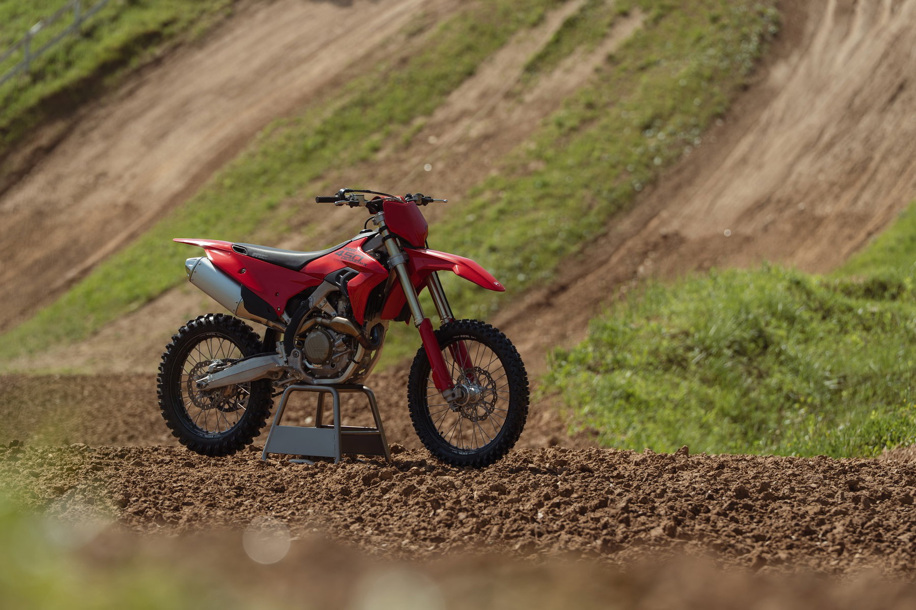 Desmo450 MX 2027: What Ducati Changes After Its First Racing Season 2 Ducati Desmo450 MX 2027 – Seitenansicht rechts in Ducati Red auf Montageständer vor grüner Streckenböschung