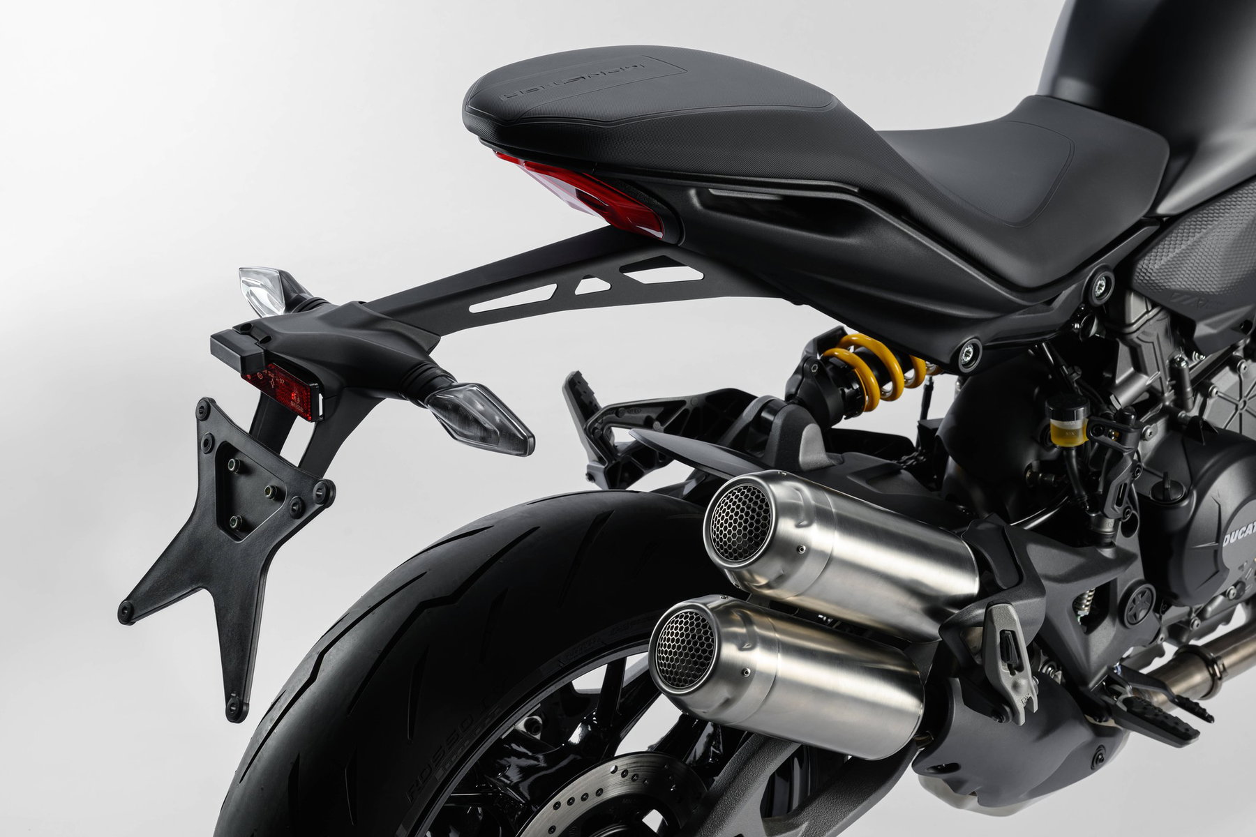 Ducati Monster Dark: Die günstigste Monster spart am Quickshifter 7 Ducati Monster Dark 2027 – Heckpartie mit Kennzeichenhalter, Doppel-Endschalldämpfer mit unlackierten Endkappen und gelber Feder des Showa-Federbeins