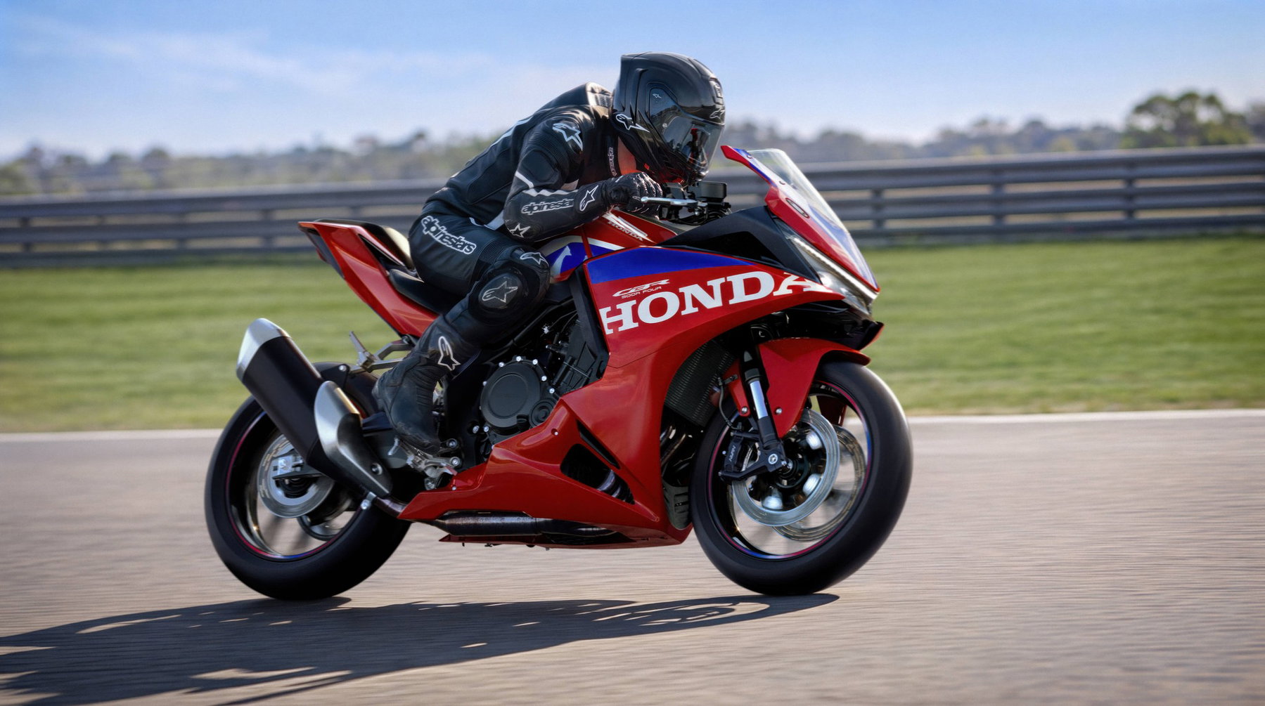 Honda CBR500R FOUR 2027 in Ignition Red Tricolour in Linkskurve auf der Rennstrecke vor blauem Himmel