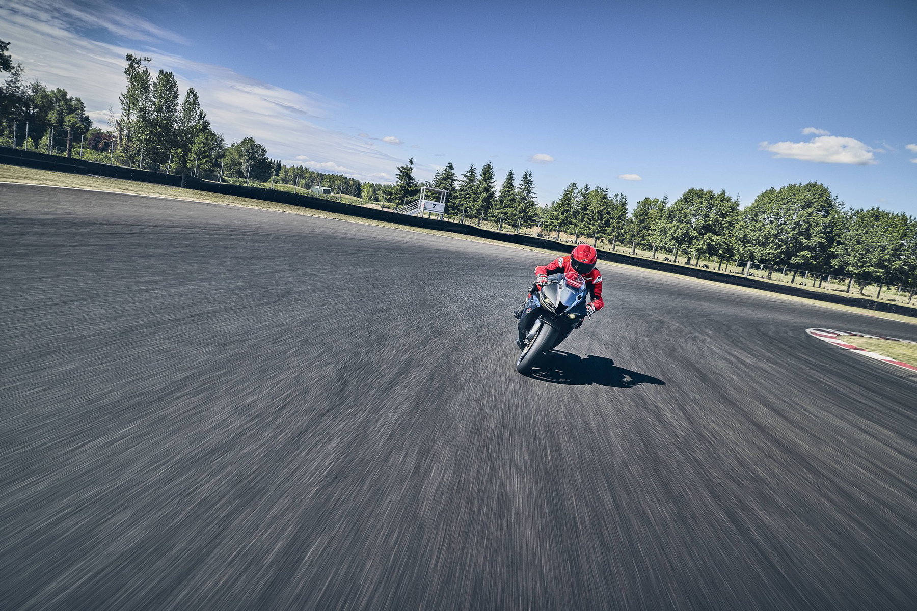 2027 Honda CBR600RR: Fireblade Brakes Keep the Four-Cylinder in the Race 6 Honda CBR600RR 2027 mit Fahrer in voller Fahrt auf der Rennstrecke, Bewegungsunschärfe im Asphalt