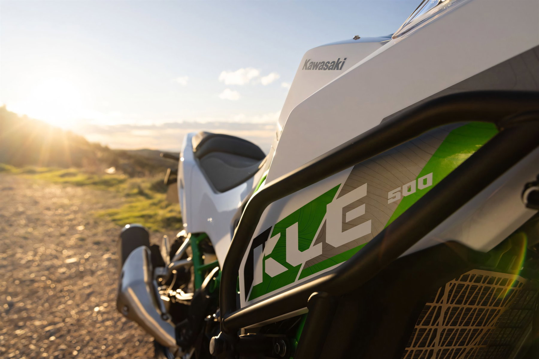 Kawasaki KLE 500 2026 – Tankverkleidung mit KLE-Schriftzug in Weiß-Grün und Sturzbügel im Gegenlicht