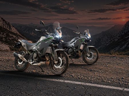 Kawasaki KLE650 SE in Pearl Storm Gray und KLE650 in Metallic Matte Graphenesteel Gray nebeneinander auf einer Bergstraße bei Sonnenuntergang