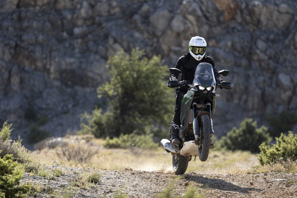 Kawasaki KLE 650 offiziell: Mehr Reise als Rallye trotz 21-Zoll-Vorderrad 5 Kawasaki KLE650 SE in Pearl Storm Gray im Stehen auf einem Schotterweg, Fahrer mit weißem Helm