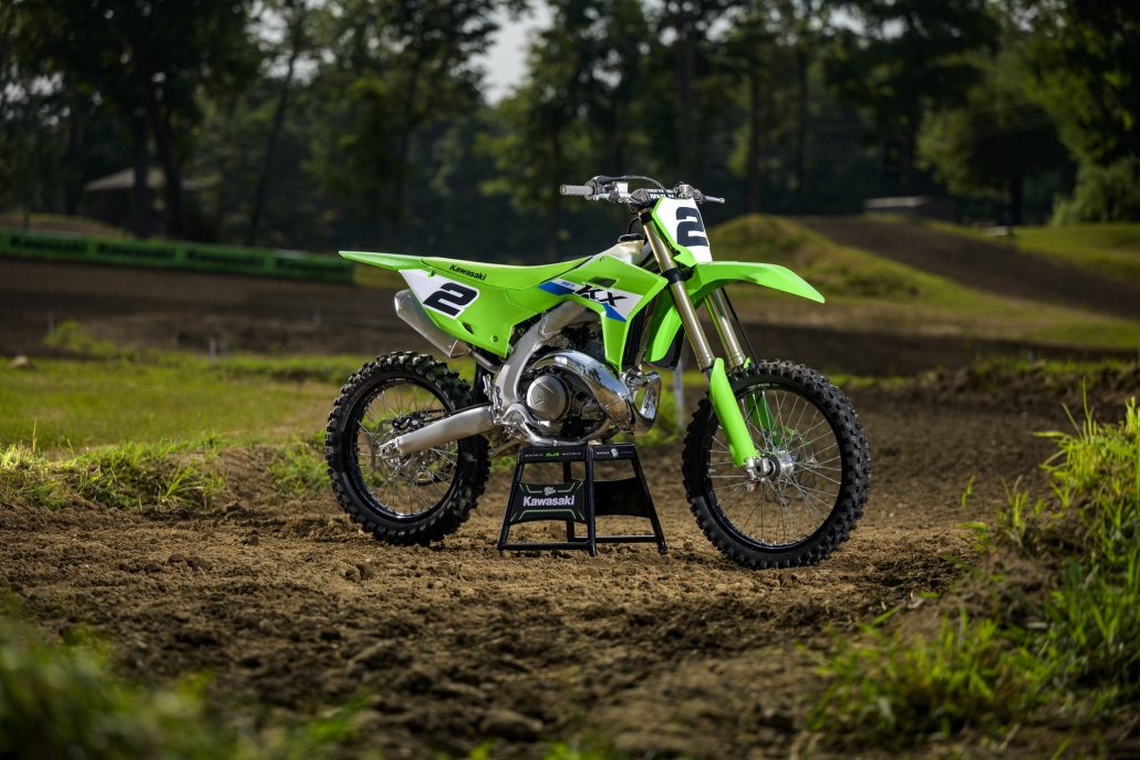 Kawasaki KX327 2027 in Lime Green mit Startnummer 2, Zweitakt-Motocrosser mit Einspritzung, auf einem Montageständer auf einer Motocross-Strecke