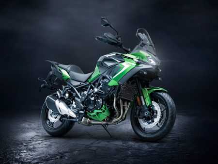 Kawasaki Versys 900 SE 2027 in Plasma Lime Green / Metallic Spark Black, Studioaufnahme schräg von vorne rechts vor dunklem Hintergrund mit leuchtendem LED-Scheinwerfer