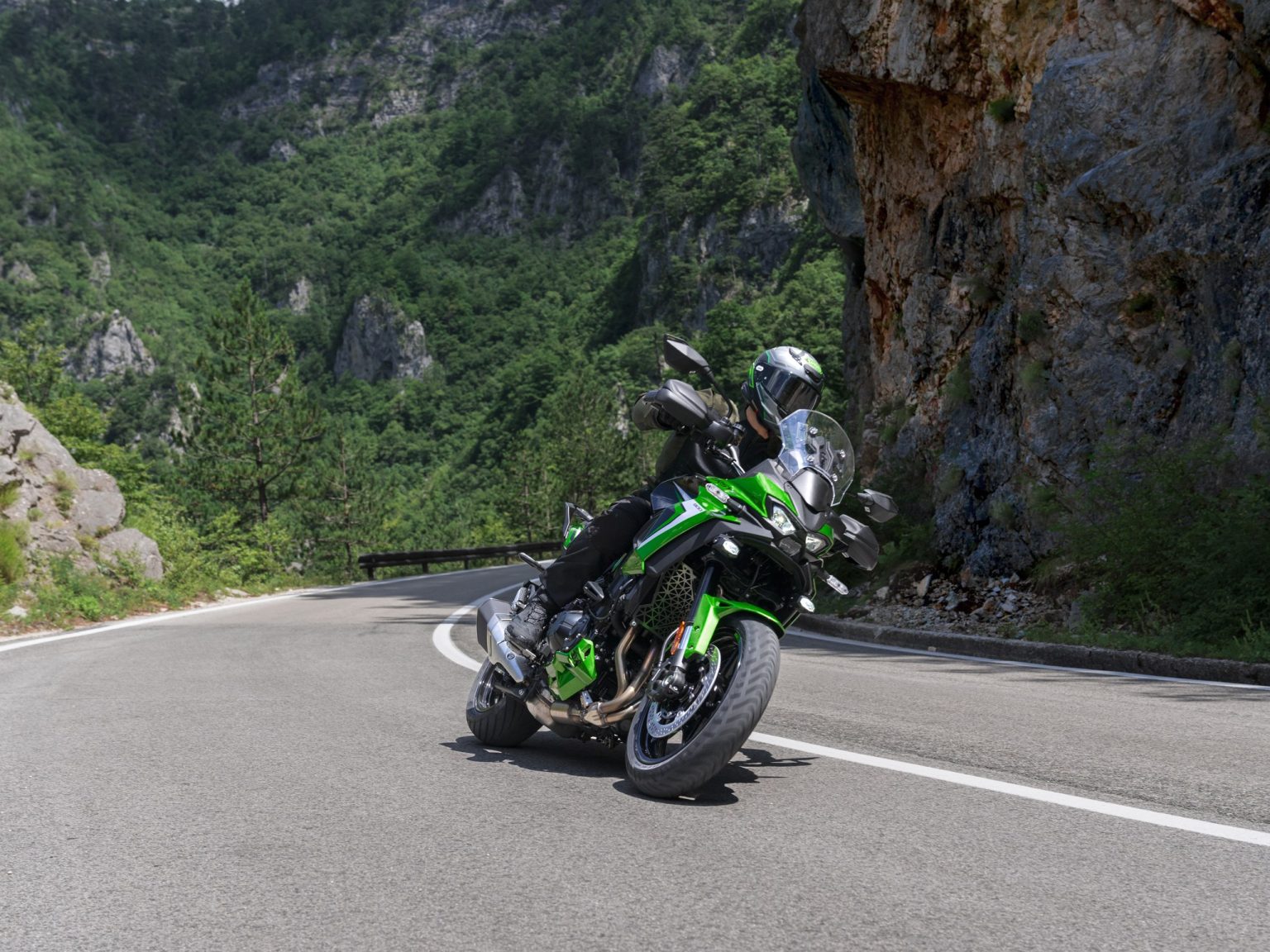 Kawasaki auf der EICMA: Was neben der Versys 900 wirklich neu ist Kawasaki Versys 900 SE 2027 in Plasma Lime Green / Metallic Spark Black in Schräglage auf einer Bergstraße vor einer Felswand
