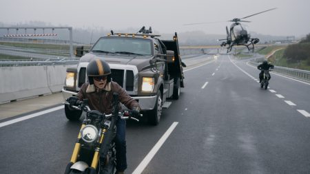 Triumph Scrambler 1200 XE in Matchbox The Movie – Fahrer mit Jethelm und Lederjacke auf nasser Autobahn, verfolgt von Abschleppwagen, Hubschrauber und zweitem Motorrad