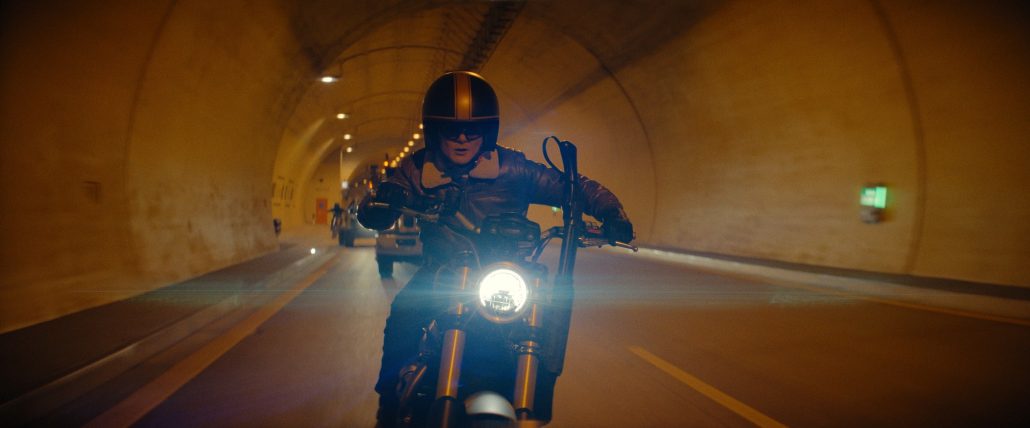 Triumph Scrambler 1200 XE in Matchbox The Movie – Frontansicht mit leuchtendem Rundscheinwerfer bei Verfolgungsjagd durch einen Straßentunnel