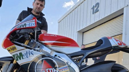 Michael Dunlop steht hinter der Gilera 250 GP in Marco Simoncellis Metis-Agip-Lackierung von 2008 vor einer Boxengarage