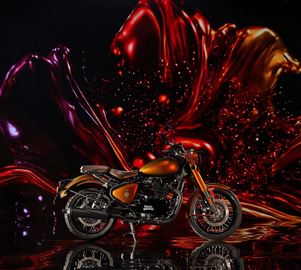 Royal Enfield Classic 650 Hypershift 125th Anniversary Edition 2026 – Seitenansicht vor roter und violetter Farbwolke mit Spritzern, Spiegelung auf dunklem Boden
