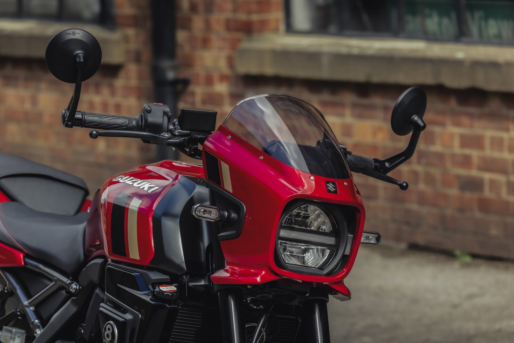 Suzuki GSX-8TT 2027: Rot-Gold-Look und Tempomat, die Technik bleibt 5 Suzuki GSX-8TT 2027 – Detail der roten Lampenmaske mit Windschild, Tank-Dekor in Rot-Gold und Lenkerendenspiegel