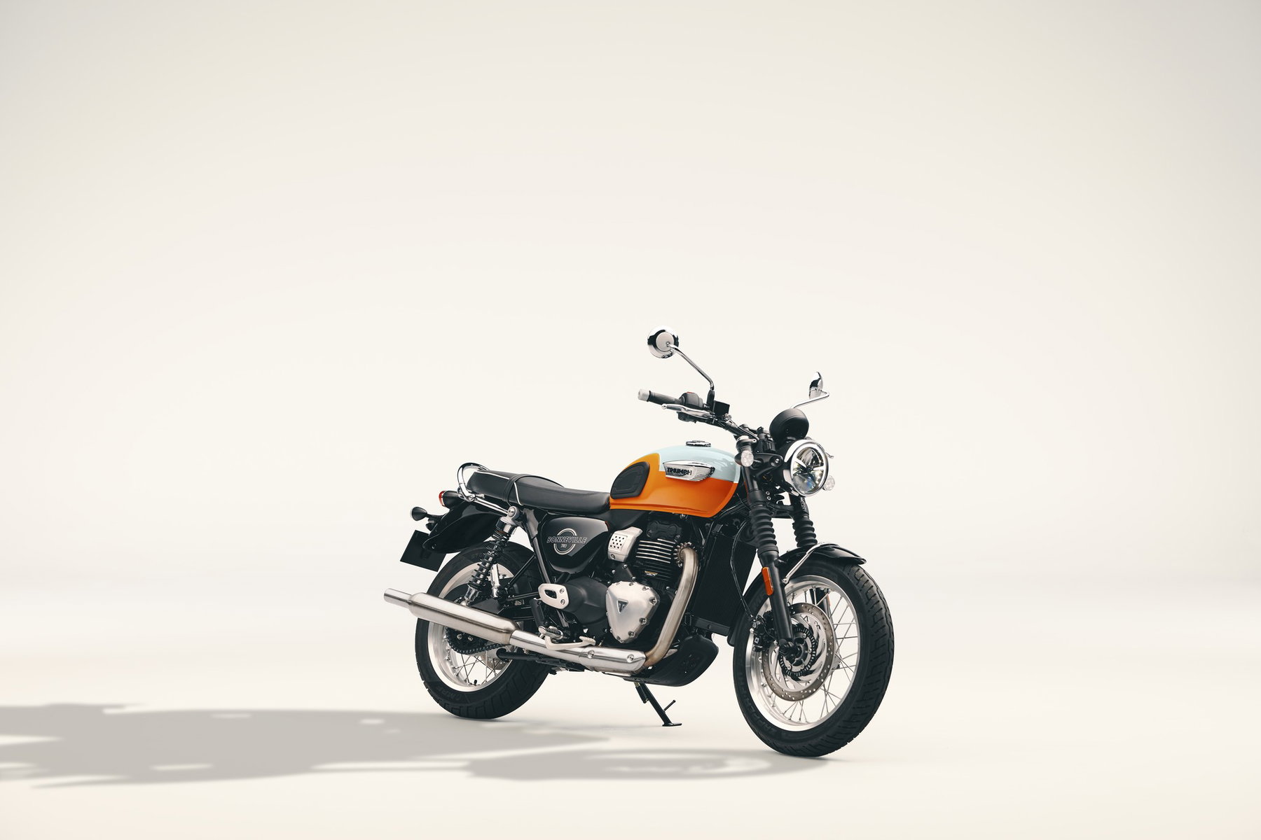Triumph Bonneville T40: Der Klassiker kommt als A2-Single mit 400 Kubik 1 Triumph Bonneville T40 2027 in Meriden Blue/Tangerine Orange schräg von vorn rechts im hellen Fotostudio, mit gebürstetem Peashooter-Schalldämpfer