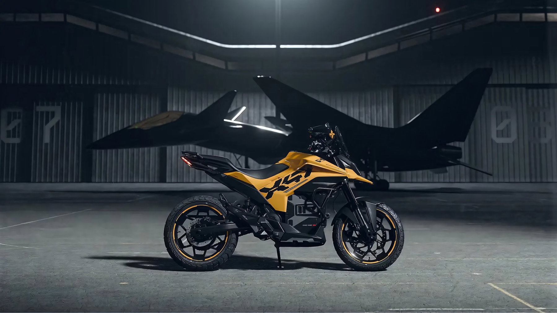 Ultraviolette X-47 Venom 2026 – Seitenansicht rechts in Afterburner Yellow in einem Flugzeughangar mit Kampfjet im Hintergrund