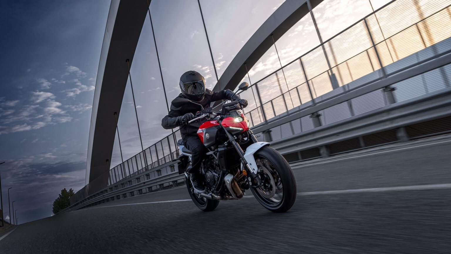 Yamaha 2027: New Colours for the Road, New Technology for the Dirt Yamaha MT-07 Y-AMT 2027 – in Redline in Schräglage auf einer Bogenbrücke