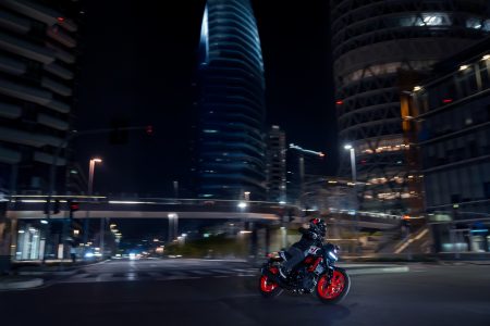 Yamaha MT-125 2027 – MT-125 in Redline White (Weiß mit roten Felgen und zweifarbiger Sitzbank) nachts in Fahrt zwischen den Hochhäusern der Stadt