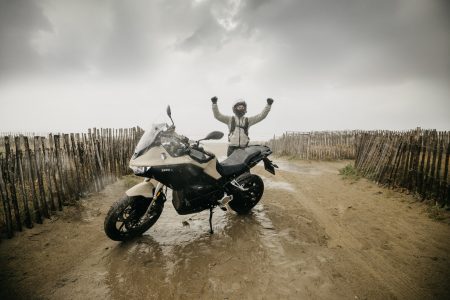 Jelle Verstaen jubelt am Strand bei Montpellier mit erhobenen Armen hinter seiner Zero DS nach der Weltrekordfahrt über 436,5 Kilometer mit einer Batterieladung