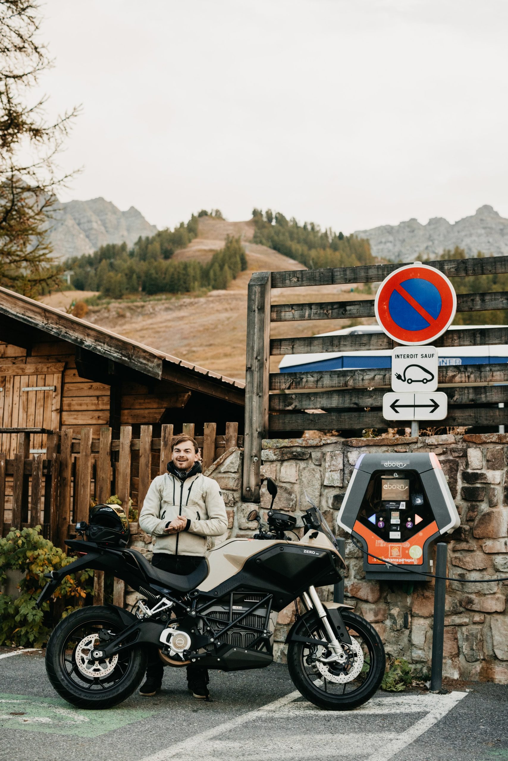 Zero DS fährt 436,5 km mit einer Ladung: So kam der Weltrekord zustande 7 Jelle Verstaen steht hinter seiner beige-schwarzen Zero DS mit Power Tank neben einer Ladesäule in einem Alpenort