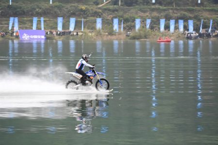 ZXMoto MX450 Weltrekord 2026 – Zhang Xue gleitet mit der umgebauten ZXMoto MX450 über den Fluss im Kreis Mayang, im Hintergrund Fahnen, Zuschauer und Rettungsboot