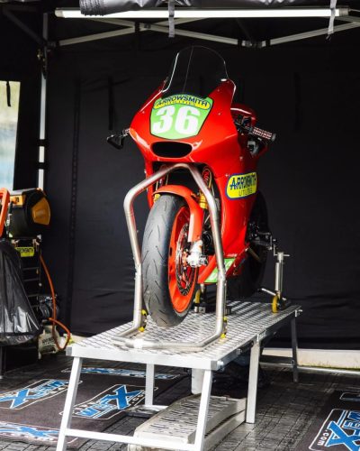 Rote Rennmaschine Nr. 36 mit Arrowsmith Sponsoring auf Montagestaender im Paddock – Isle of Man TT 2026