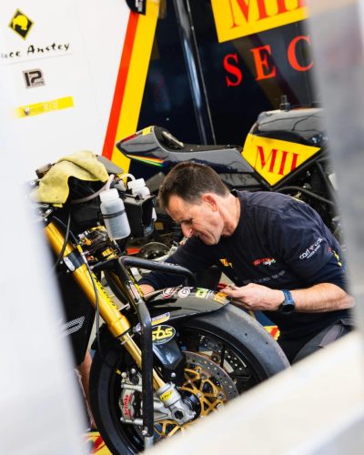 Mechaniker arbeitet an Bruce Ansteys Milenco-Rennmaschine Nr. 12 im Paddock – Isle of Man TT 2026