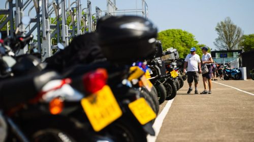 Paar spaziert entlang geparkter Motorräder vor der TT-Tribüne – Isle of Man TT 2026 Paddock