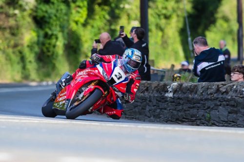 Dean Harrison auf der roten Honda Racing UK Nummer 3 in Schräglage vor Zuschauern an Steinmauer – Isle of Man TT 2026 Qualifying