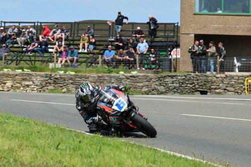 Solofahrer in Schräglage vor Zuschauertribüne auf dem Mountain Course – Isle of Man TT 2026 Qualifying