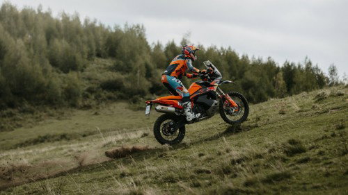 KTM 890 Adventure R Rally 2026 im Sprung ueber Grashügel – Seitenansicht rechts Offroad