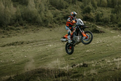 KTM 890 Adventure R Rally 2026 in der Luft ueber Wiese – Seitenansicht Sprung Offroad