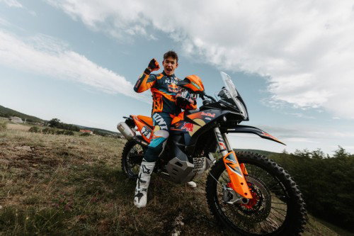 Fahrer posiert jubelnd neben KTM 890 Adventure R Rally 2026 – Outdoor Portrait mit blauem Himmel