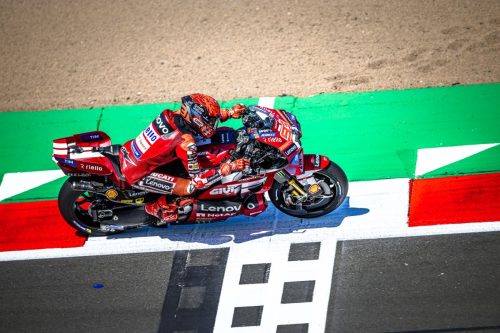 Marc Marquez aus erhöhter Perspektive in Schräglage auf der roten Ducati Desmosedici GP26 über dem Randstein – MotoGP Großbritannien GP Silverstone 2026