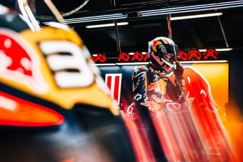 Brad Binder mit Helm in der abgedunkelten Box, im Vordergrund unscharf seine KTM RC16 mit der Startnummer 33 – MotoGP Großbritannien GP Silverstone 2026