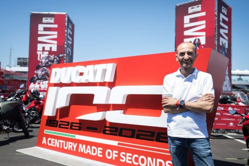 Ducati-Manager neben dem großen Schild Ducati 100 – A Century Made of Seconds bei der World Ducati Week 2026 in Misano
