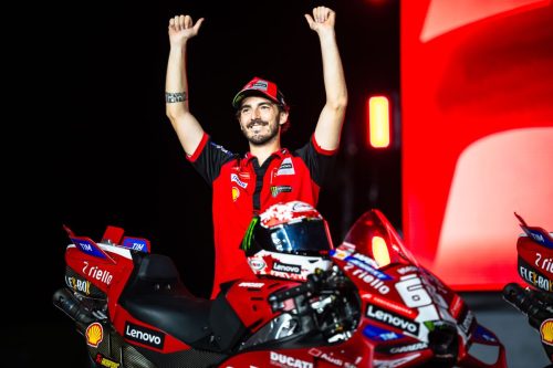 Fahrer jubelt mit erhobenen Armen auf der Bühne neben seiner roten Ducati bei der Live the Legend Night in Misano