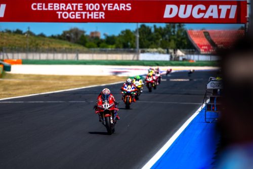 Einzelner Fahrer auf roter Ducati auf der Strecke vor dem Celebrate-100-Years-Together-Banner in Misano