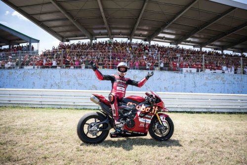 Fahrer kniet neben seiner roten Ducati-Rennmaschine vor voller Tribüne bei der World Ducati Week 2026 in Misano