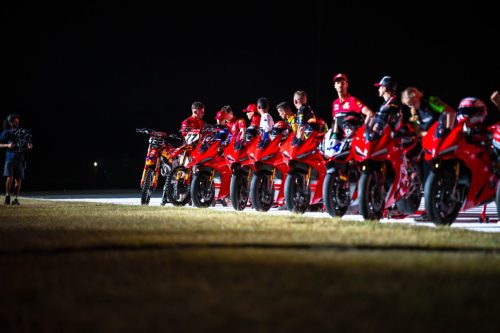 Reihe von Ducati-Fahrern mit ihren Motorrädern bei Nacht auf der Strecke der Live the Legend Night in Misano