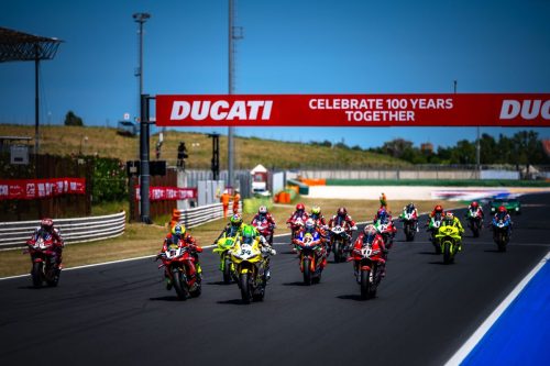 Ducati-Werksfahrer mit ihren Motorrädern aufgereiht auf der Strecke des Misano World Circuit bei der World Ducati Week 2026
