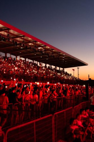 In rotes Licht getauchte Tribüne mit Publikum in der Abenddämmerung bei der World Ducati Week 2026 in Misano
