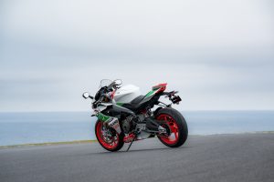 Aprilia RS 660 Phillip Island Tribute schräg von hinten links mit roten Felgen und grün-weißem Heck an der Küste von Phillip Island