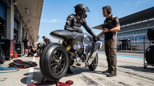 Bandit9 Ducati 821 – Fahrer im Rennanzug naehert sich dem in der Boxengasse abgestellten Motorrad