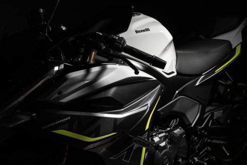 Detailaufnahme der Benelli Tornado 550 2026 in dramatischem Studiolicht: weißer Tank mit schwarzem Benelli-Schriftzug, Cockpitbereich mit Lenkerarmaturen und goldenen Gabelstandrohren, dunkler Hintergrund