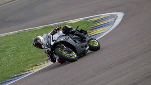 Benelli Tornado 550 2026 in Tech Silver beim Fahrtest auf dem Autodromo di Modena, Fahrer mit weiß-rotem Helm in enger Schräglage durch eine Rechtskurve, Fahrbahn mit blau-gelber Curb-Markierung