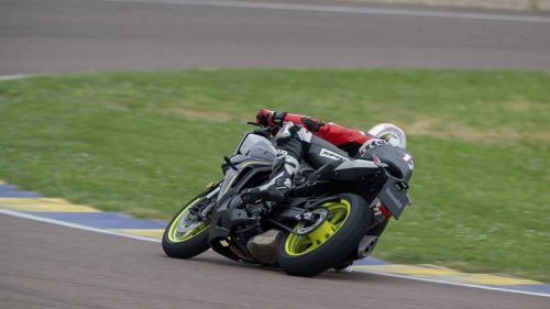 Benelli Tornado 550 2026 in Tech Silver beim Fahrtest auf dem Autodromo di Modena, Fahrer in roter Lederkombi mit Startnummer 17 in starker Schräglage durch eine Kurve, Curb-Markierung am Fahrbahnrand