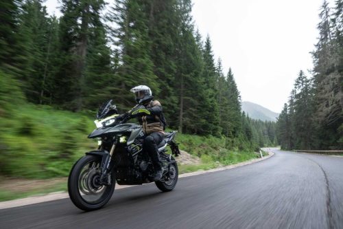 Benelli TRK 902 Xplorer (2026) – Fahraufnahme auf kurviger Waldstrasse in den Dolomiten, Fahrer in Vollmontur