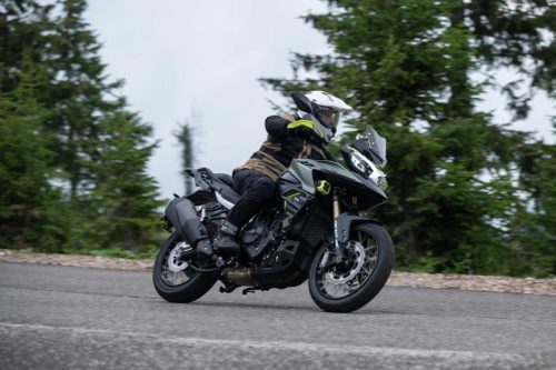 Benelli TRK 902 Xplorer (2026) – Fahraufnahme in Olivgruen/Schwarz mit Neongelb-Akzenten, Fahrer in Schraeglage auf Passstrasse