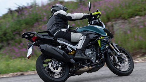 Benelli TRK 902 Xplorer (2026) – Fahraufnahme von hinten auf Wiesenweg mit Weidenroeschen; Kennzeichen am Heck ist lesbar